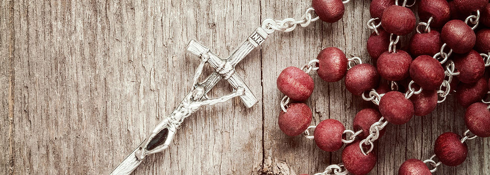 A red rosary with a silver crucifix on a wooden table
