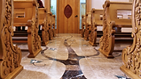 A marble floor of a chapel with wooden pews
